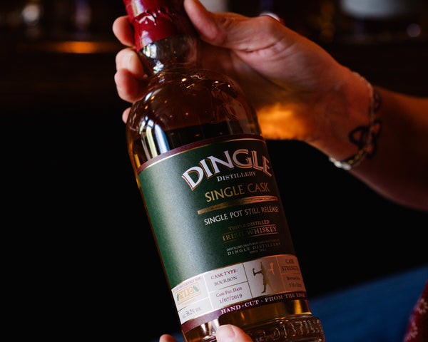 Person holding a bottle of Dingle Single Malt Whiskey with a blurred background