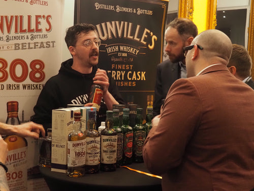 People around a table with Dunville's Irish Whiskey bottles at an event.