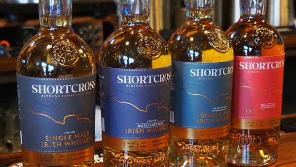 Four bottles of Shortcross whiskey on a bar counter with a blurred background