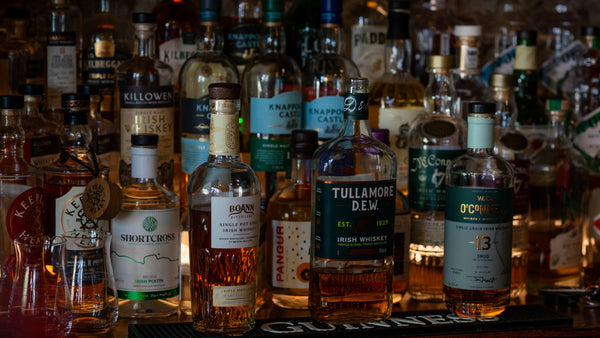 Collection of whiskey bottles on a bar shelf with labels visible