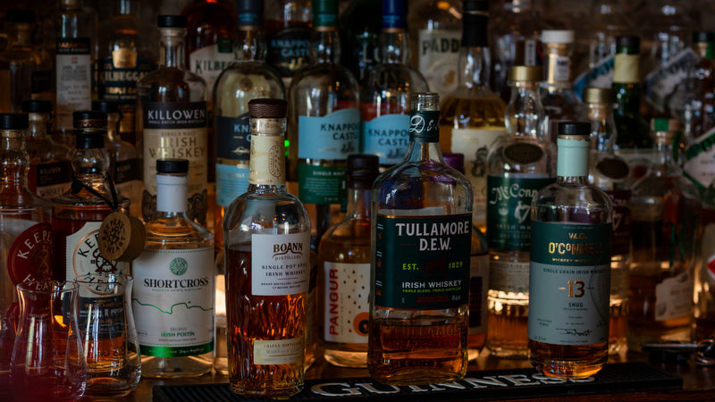Collection of whiskey bottles on a bar shelf with labels visible